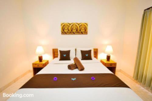 a bedroom with a large bed with two lamps at Canggu Kayuma House in Canggu