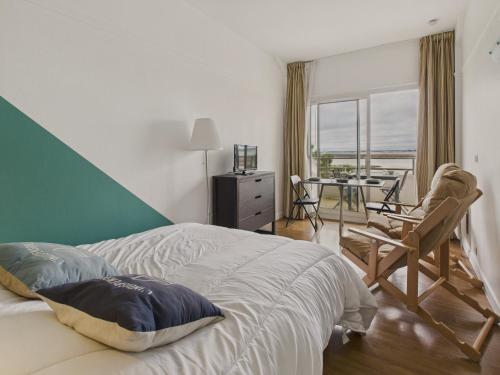 a bedroom with a bed and a table and chairs at Vue mer avec balcon - Studio pour 2 avec piscine in Le Croisic