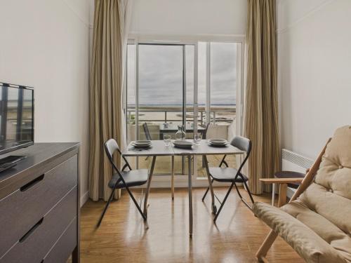 une salle à manger avec une table et des chaises et une fenêtre dans l'établissement Vue mer avec balcon - Studio pour 2 avec piscine, au Croisic