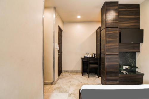 a room with a bed and a desk and a television at Super Collection O Belgacihia Near Kolkata Railway Station in kolkata