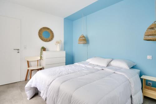 ein blaues Schlafzimmer mit einem weißen Bett und einem Stuhl in der Unterkunft Jolie maison pour 8 - 400m de la plage - terrasse in La Guérinière