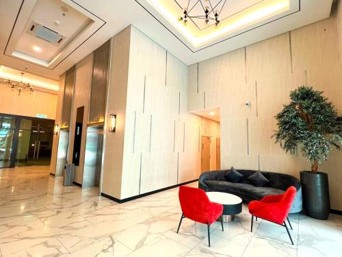 a lobby with a couch and two red chairs at Greenfield Residence Bandar Sunway in Petaling Jaya