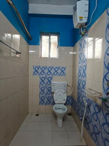 a bathroom with a toilet and a blue wall at Prashaanti Tourist lodge and Restaurant in Bongaigaon