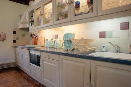 une cuisine avec des armoires blanches et un comptoir dans l'établissement Belle maison avec piscine chauffée pour 6, à Saint-Léon-sur-Vézère