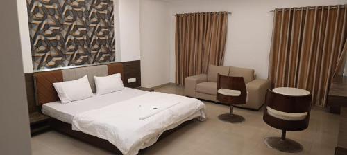 a bedroom with a bed and a chair and a couch at hotel nova haven in Ankleshwar