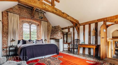 a bedroom with a bed and a brick wall at A Luxury Tudor Hall & Gardens Located on Breath-Taking Norfolk Estate in Norwich