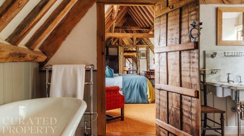 a bathroom with a bath tub and a bedroom at A Luxury Tudor Hall & Gardens Located on Breath-Taking Norfolk Estate in Norwich