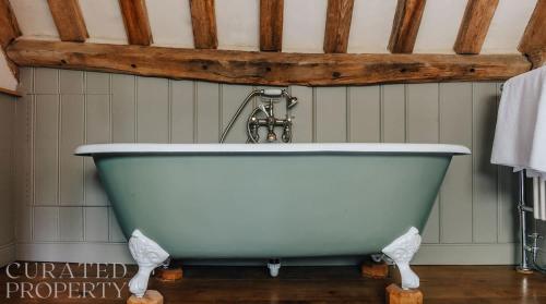 a white bath tub in a bathroom with at A Luxury Tudor Hall & Gardens Located on Breath-Taking Norfolk Estate in Norwich