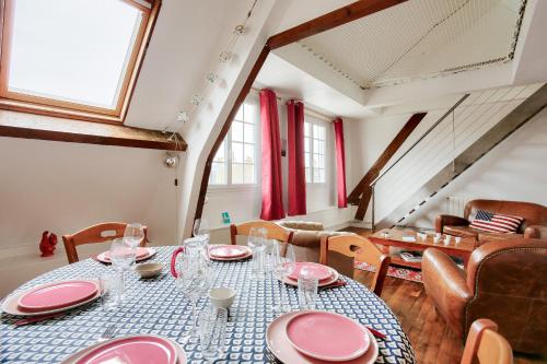 une salle à manger avec une table et des plats roses dans l'établissement Appartement pour 6 en plein centre de Dinard, à Dinard