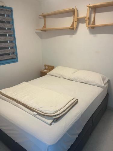 un lit avec des draps blancs et une étagère au mur dans l'établissement Cabourg plage 2 pieces, à Cabourg