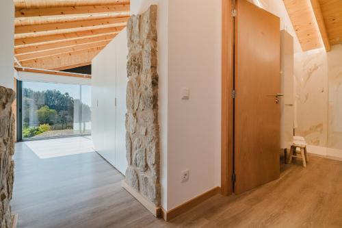an open hallway with a stone wall and a door at Dunas e Abraços in Braga