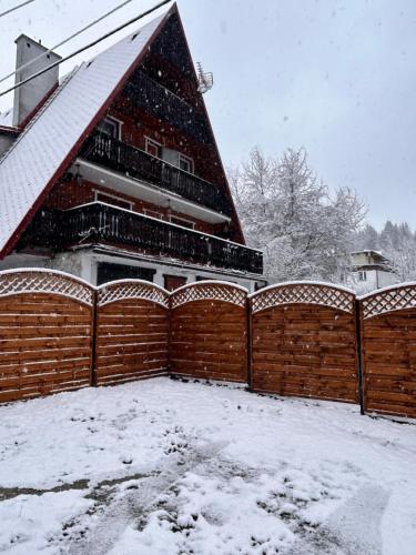 a house with a fence in the snow at Willa Zielona Kraina in Wisła