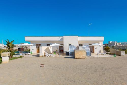 Caprarica di LecceにあるIl Giardino dei Gelsi by BarbarHouseの駐車場に椅子と傘が置かれた建物