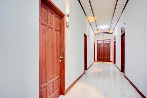 an empty corridor with wooden doors and white walls at Hotel O Krakatau Near Universitas Muhammadiya Sumatra Utara UMSU in Medan