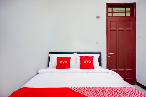 a bedroom with a red door and a bed with two red pillows at Hotel O Krakatau Near Universitas Muhammadiya Sumatra Utara UMSU in Medan