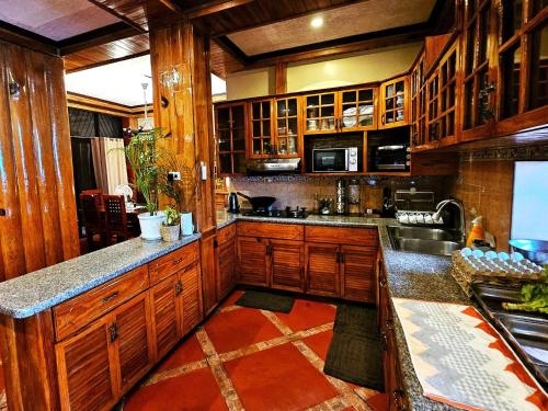 a large kitchen with wooden cabinets and a sink at Transient Guest Room 3A Baguio Wifi Parking in Baguio