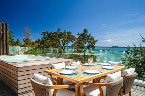 a wooden table with wine glasses and chairs next to a swimming pool at Aqua Serena - Luxury Beachfront Penthouse in Grand Gaube