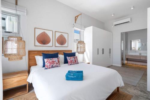a bedroom with a large white bed with blue pillows at Aqua Serena - Luxury Beachfront Penthouse in Grand Gaube
