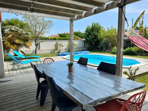 une terrasse en bois avec une table et des chaises ainsi qu'une piscine dans l'établissement maison avec piscine bord de mer, à Longeville-sur-Mer