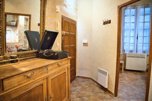 a bathroom with a mirror and a dresser with a suitcase at Appartement Centre Historique - Garage Privé in Uzès