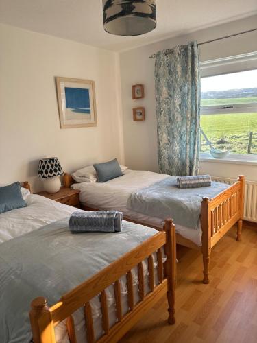 a bedroom with two twin beds and a window at Portballintrae 3 bedroom cosy coastal bungalow in Portballintrae