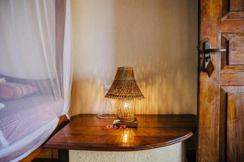 a lamp on a wooden table next to a bed at Isolabella Ayurveda Hotel Hiriketiya in Nilwella