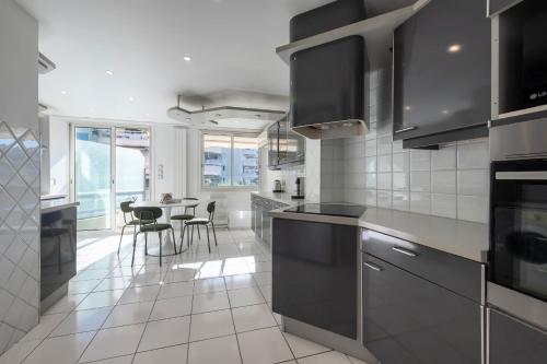 une cuisine avec des appareils en acier inoxydable et une table avec des chaises dans l'établissement Spacious 2-Br Apartment Walk to Beach & City Center, à Cannes