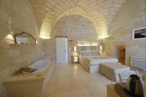 Palazzo Corte Dei Granai Raro Villas Homes Collection في ماليي: غرفة نوم كبيرة مع سرير وحوض استحمام