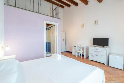 a white bedroom with a white bed and a tv at Al Palmento Relais in Siracusa