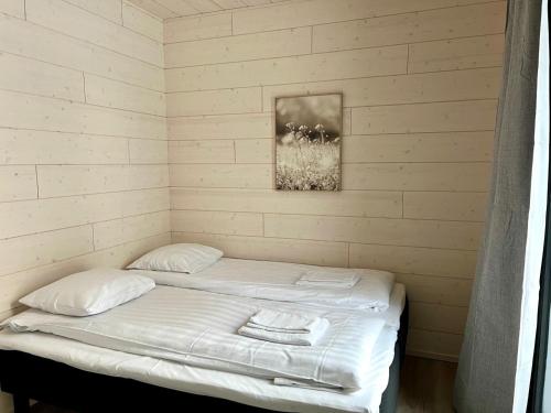 a bed in a room with white sheets and pillows at Kotimaailma Apartments Patokuja in Kempele