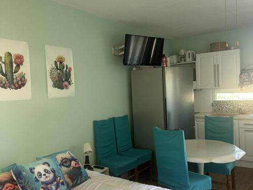 La cuisine est équipée d'une table, de chaises bleues, d'une table et d'un réfrigérateur. dans l'établissement Studio rénové proche des cures avec climatisation - FR-1-680-45, à Balaruc-les-Bains