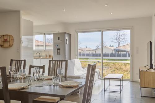 une salle à manger avec une table et des chaises et une grande fenêtre dans l'établissement Maëva - Proche des Plages, à Parentis-en-Born