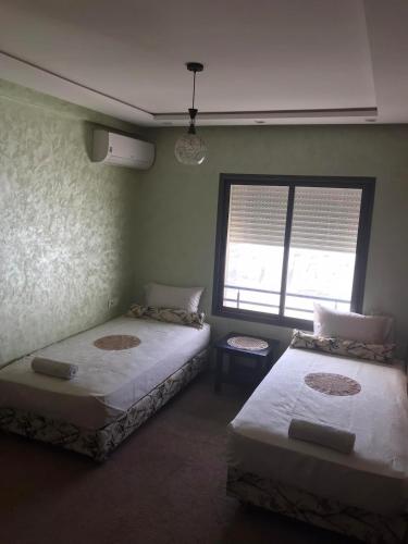 two beds in a room with a window at Comfort Stay by Mohammed V Airport in Nouaseur