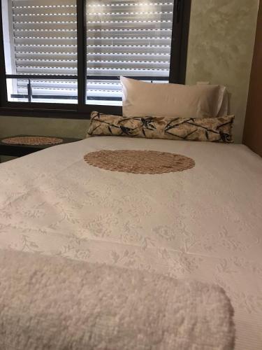 a bed with a white comforter and a window at Comfort Stay by Mohammed V Airport in Nouaseur
