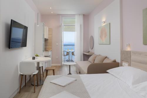 a white bedroom with a bed and a living room at Villa Primordia in Podgora