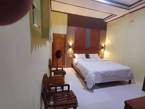 a bedroom with a bed and a chair at GAROGA Guest House in Ambarita