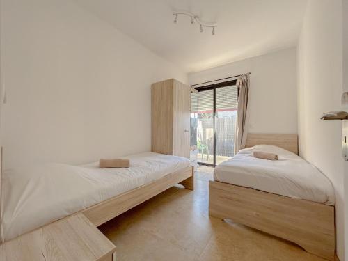 two beds in a room with a window at Centrale climatisée deux chambres terrasse parking, saint raphael in Saint-Raphaël