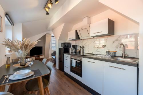 a kitchen with white cabinets and a dining table at Daniels Apartment an der Schloßbrücke in Meißen