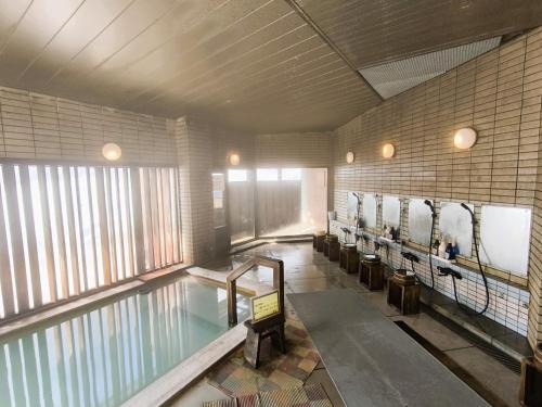 a swimming pool with a row of chairs in a room at Mogamitakayu Zenshichinoyu Ohira in Zao Onsen