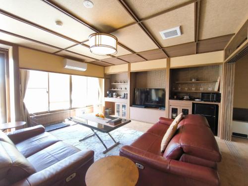 a living room with a couch and a table at Mogamitakayu Zenshichinoyu Ohira in Zao Onsen