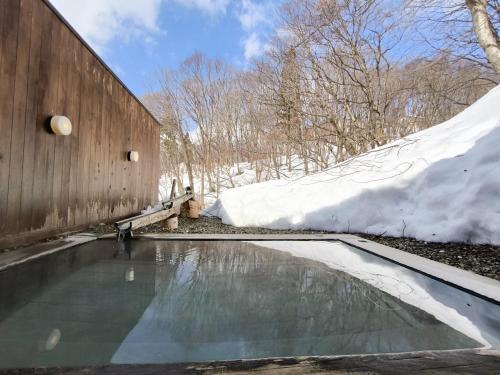a swimming pool with snow next to a building at Mogamitakayu Zenshichinoyu Ohira in Zao Onsen