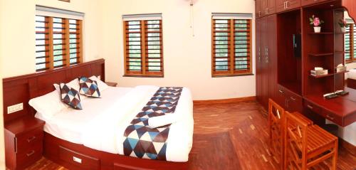 a bedroom with a large bed and wooden floors and windows at DAWN STAR villa in Kalpetta
