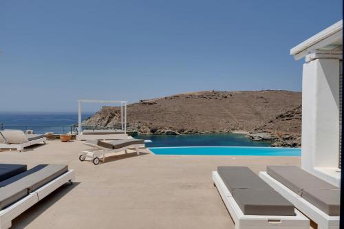 a patio with lounge chairs and a swimming pool at Blueros - Black Stone Suite in Megas Yialos-Nites