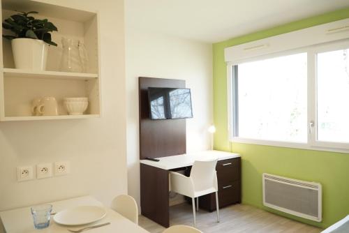 Una pequeña habitación con un escritorio y una ventana. en Apparteo Nantes, en Nantes