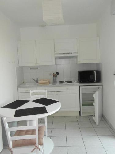 une cuisine avec des armoires blanches et une table et des chaises dans l'établissement Appt Studio CHATELAILLON PLAGE - CL060-023, à Châtelaillon-Plage