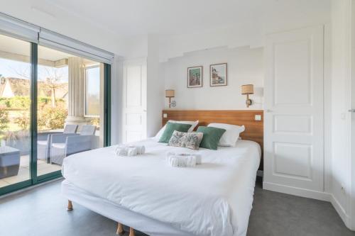 Cette chambre comprend un lit blanc et une grande fenêtre. dans l'établissement Le Golfeur - Parking - 100m Golf, à Saint-André-des-Eaux