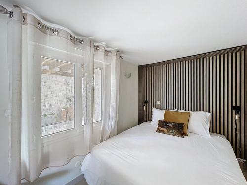 Un dormitorio con una cama blanca y una ventana. en Appartement le loft, en Saintes-Maries-de-la-Mer
