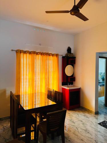 a dining room with a table and a yellow curtain at MOON 3bhk ENTIRE VILLA 02 Varkala with kitchen in Varkala