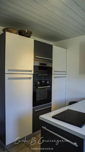 - une cuisine avec des appareils électroménagers blancs et un comptoir dans l'établissement La VILLA DU CABELLOU, à Concarneau