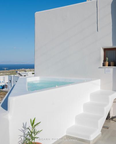 a pool on the side of a white house at Nohēme Luxury Suites in Vourvoulos